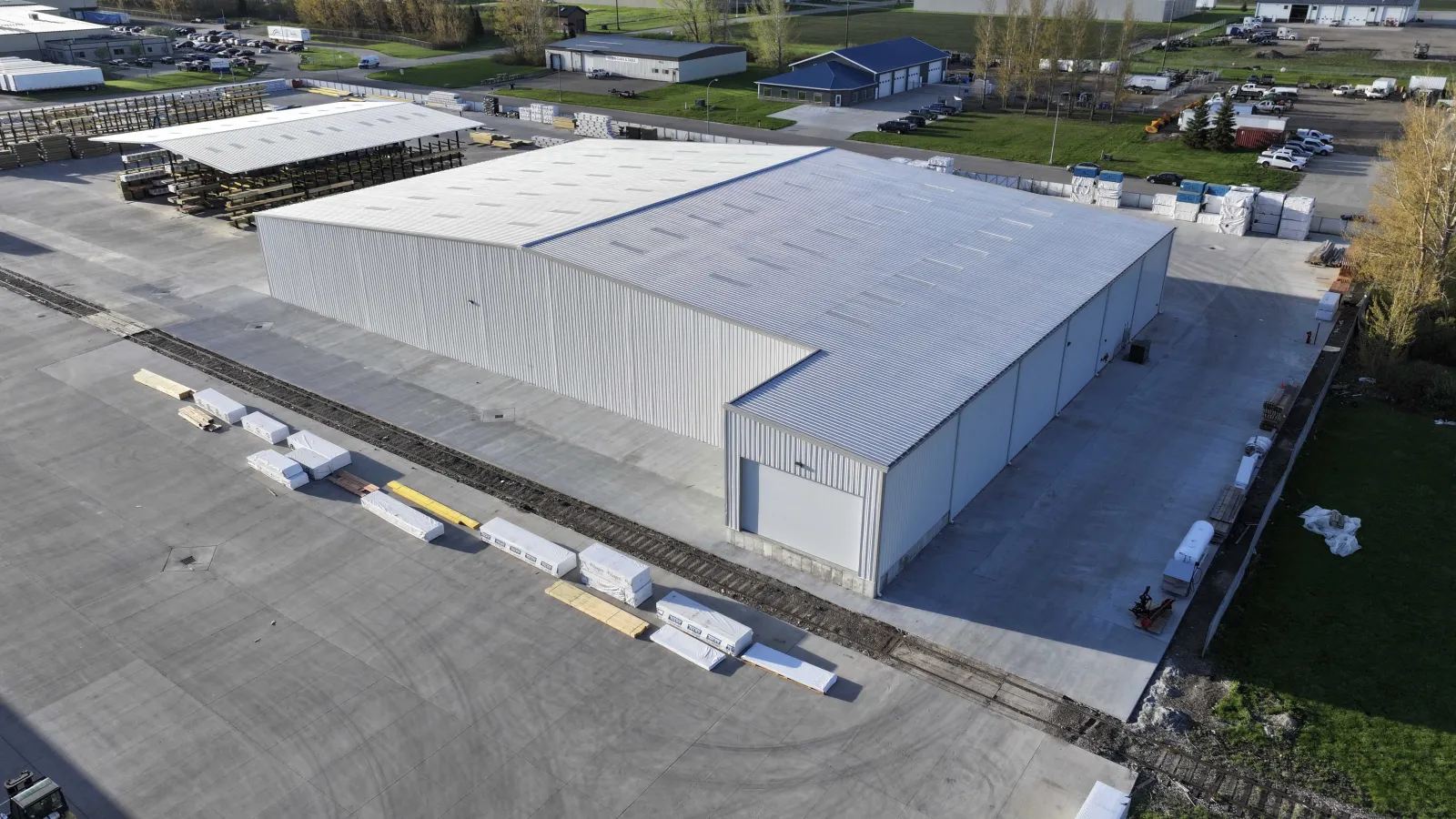 Aerial view of a large industrial warehouse with surrounding storage and concrete pavement in a spacious facility.