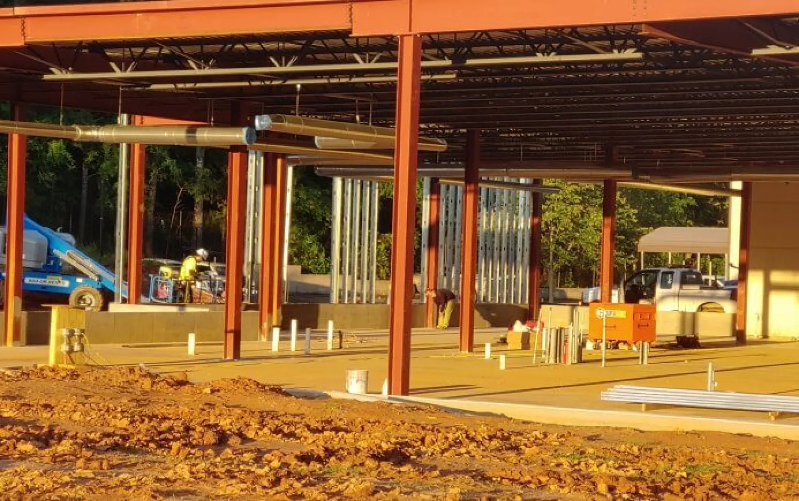 Steel framework and concrete foundation of a building under construction with workers and equipment visible