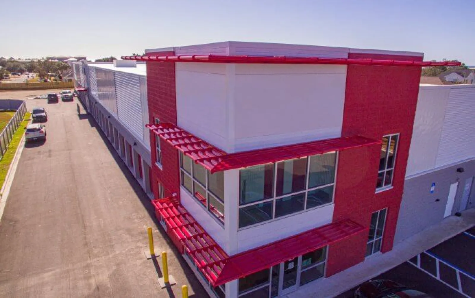 Modern industrial building with white and red exterior and large windows under clear sky.