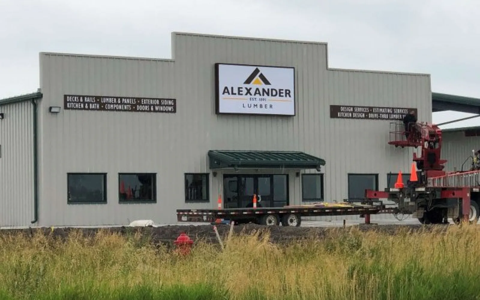 Alexander Lumber building with signage displaying services like decks, rails, kitchen design, and exterior siding