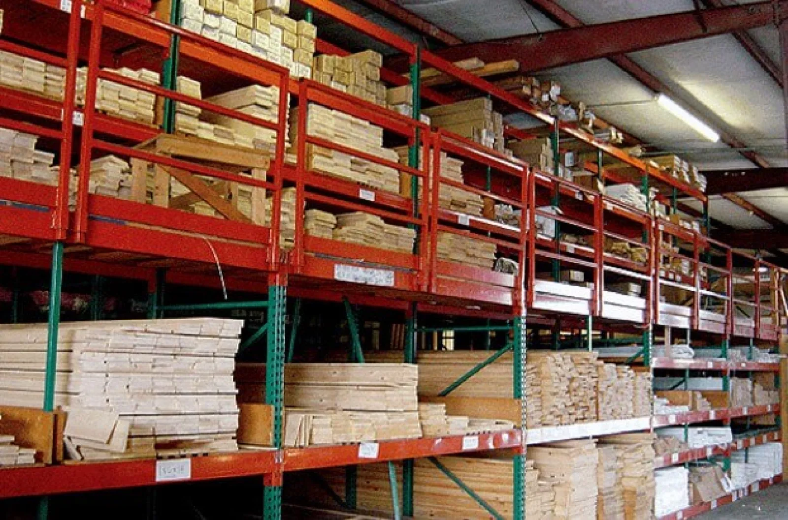 Warehouse shelves stocked with various sizes of lumber and wooden planks organized for storage.