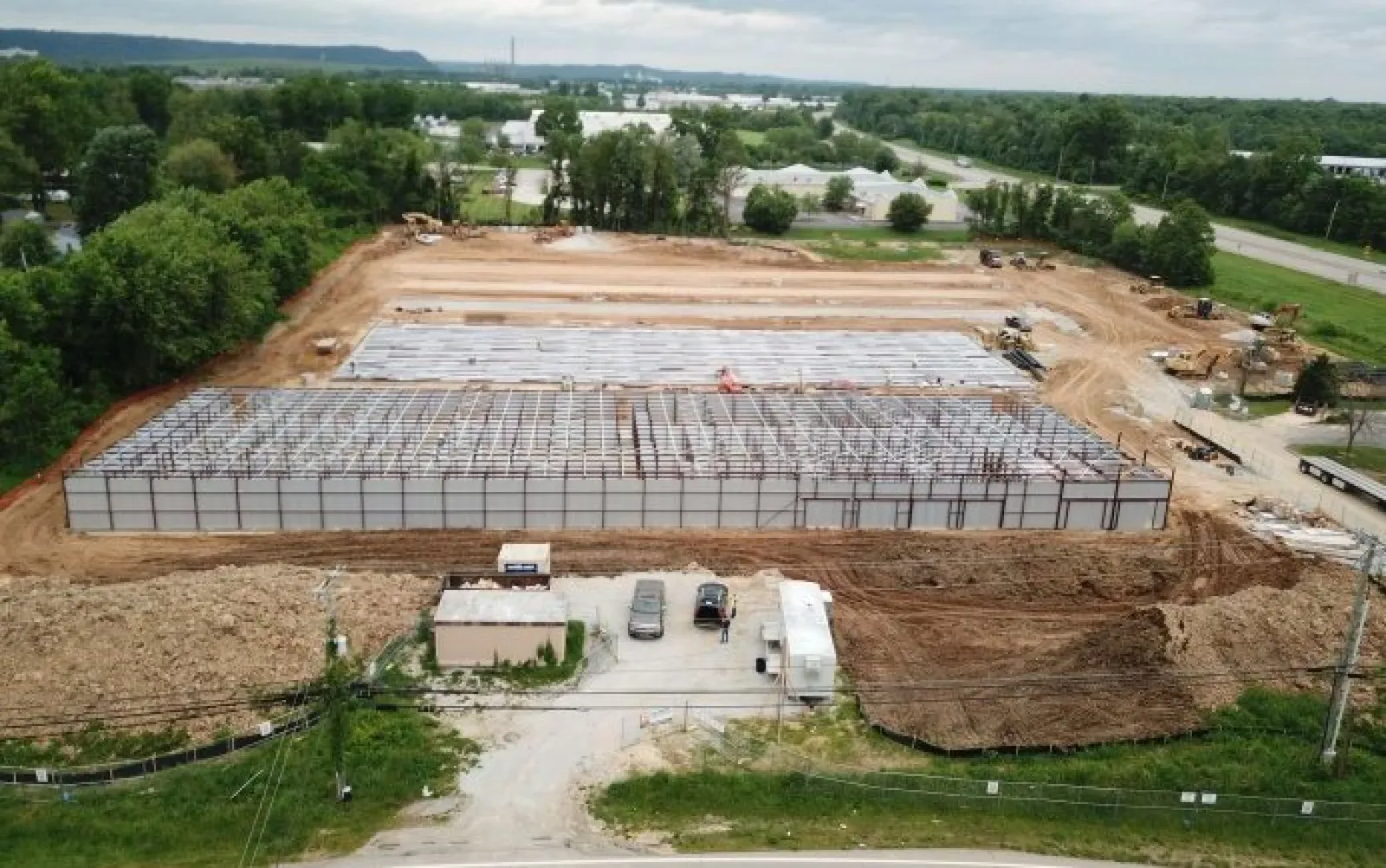 Aerial view of a large industrial building under construction with steel framework and cleared earth around it.
