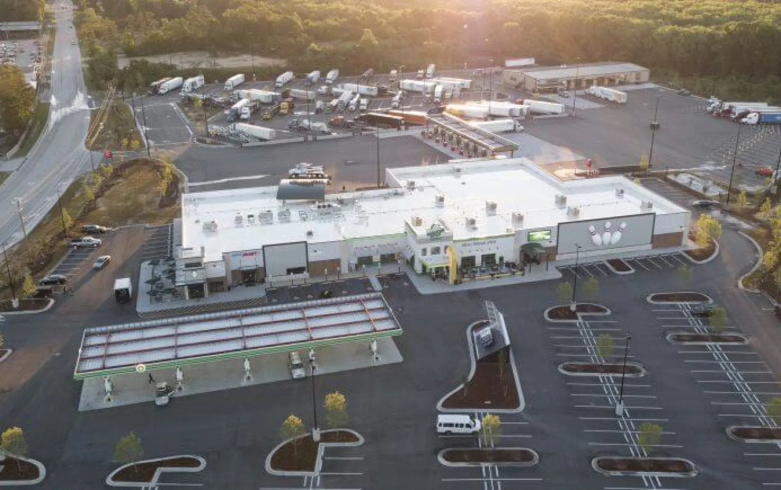 Aerial view of a large convenience store with gas station and trailer parking area during sunset.
