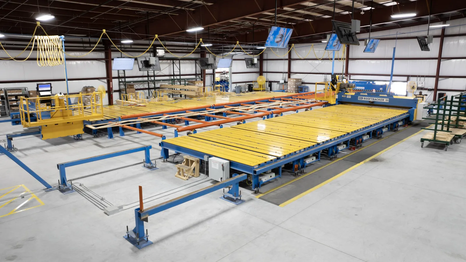 Large industrial machine with yellow and blue components in a spacious factory setting under bright lights