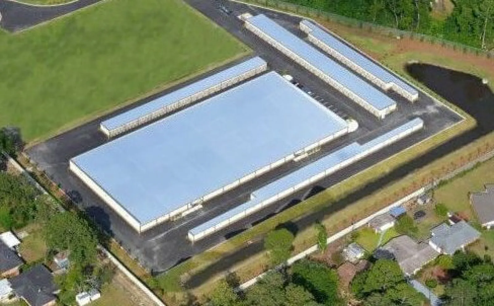 Aerial view of a large warehouse complex with multiple long slim storage units and surrounding greenery.