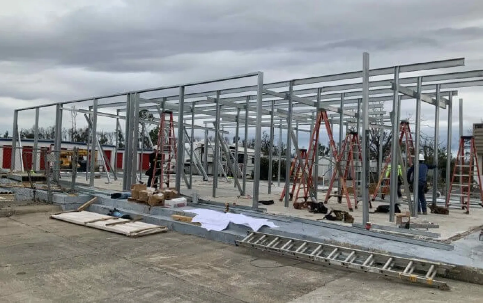 Steel frame of a building under construction with ladders and construction materials on a cloudy day