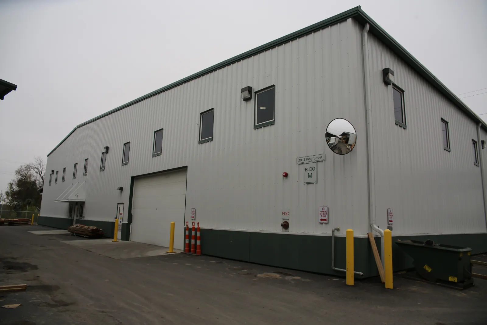 Exterior view of a large white industrial warehouse with multiple windows and a loading dock door.
