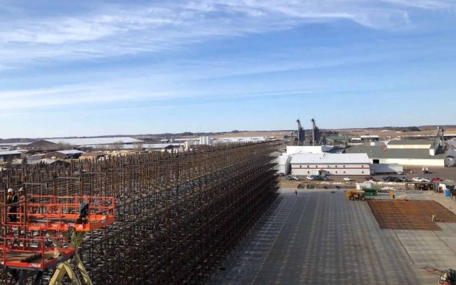 Large industrial storage rack construction at a manufacturing facility under clear blue skies.