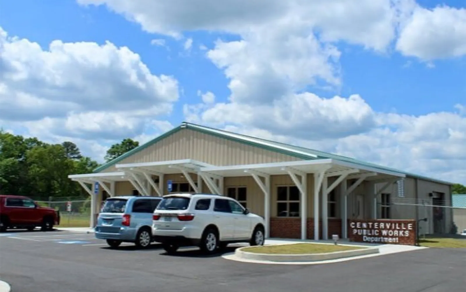 Centerville Public Works Department building with parked cars under blue sky and white clouds