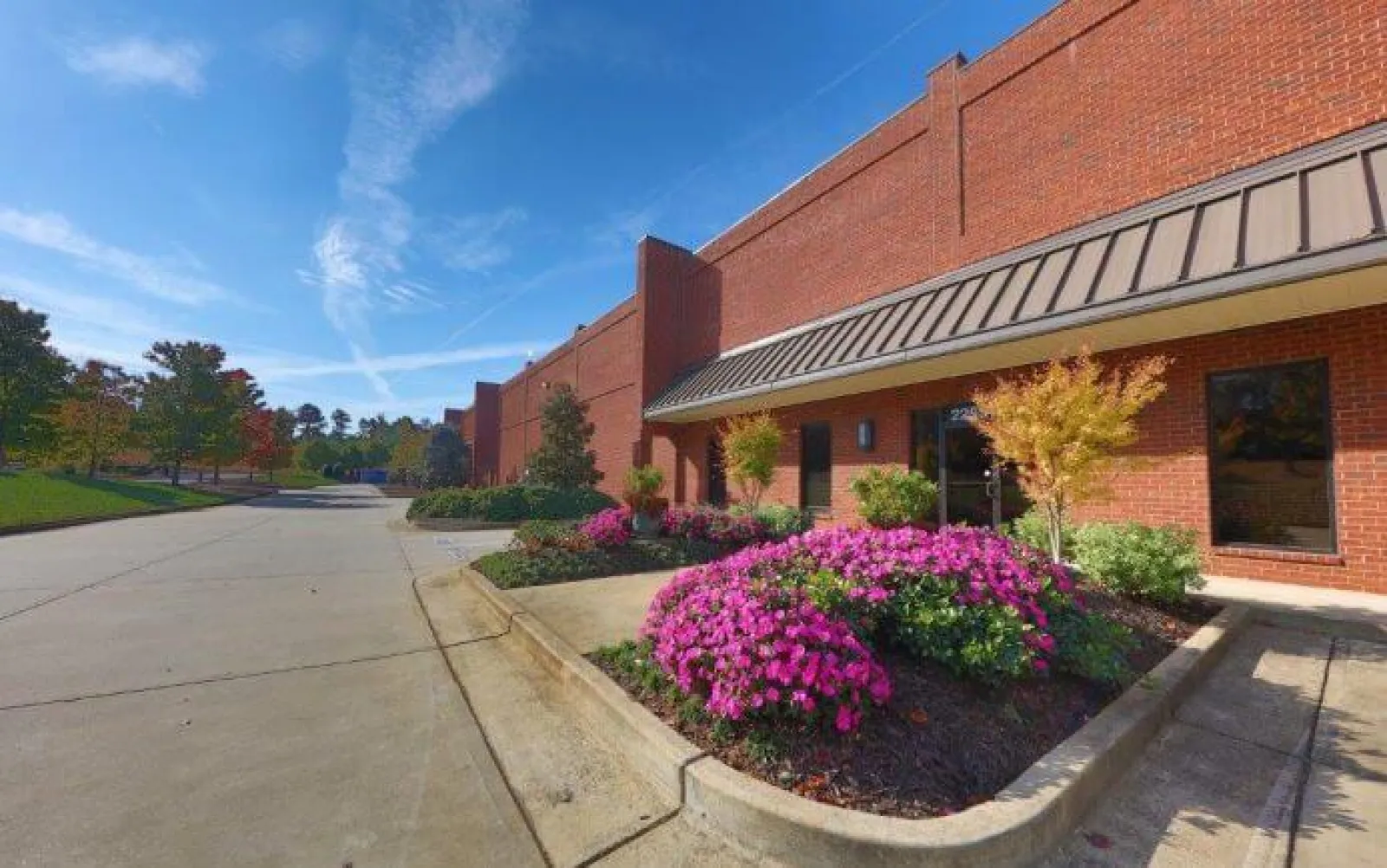 Brick commercial building with landscaped flower beds and clear blue sky on a sunny day.