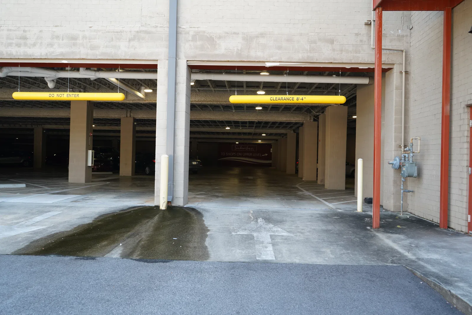 Entrance to an underground parking garage with clearance and no entry signs, and wet pavement.