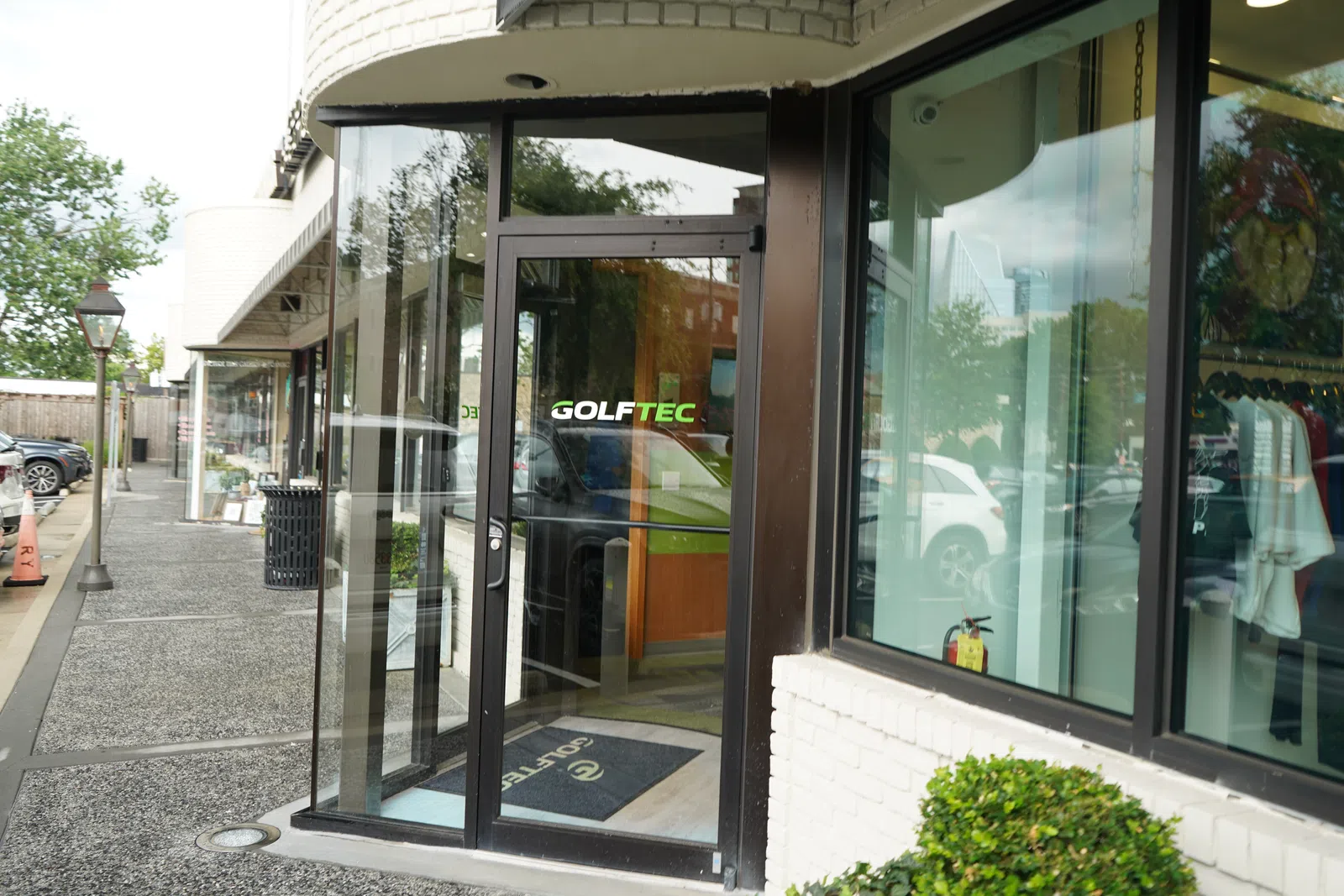 GolfTEC storefront with glass door and windows showing golf apparel and equipment inside a modern shopping area.