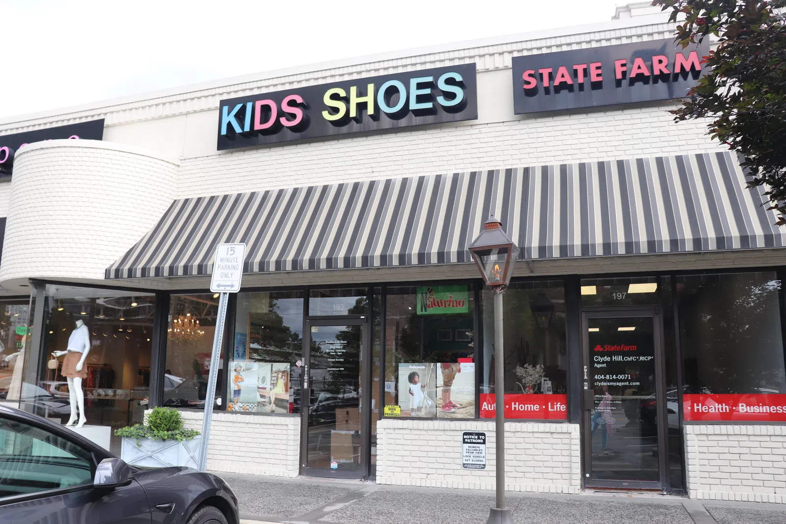 Storefront with colorful Kids Shoes sign and adjacent State Farm insurance office in a small shopping plaza.