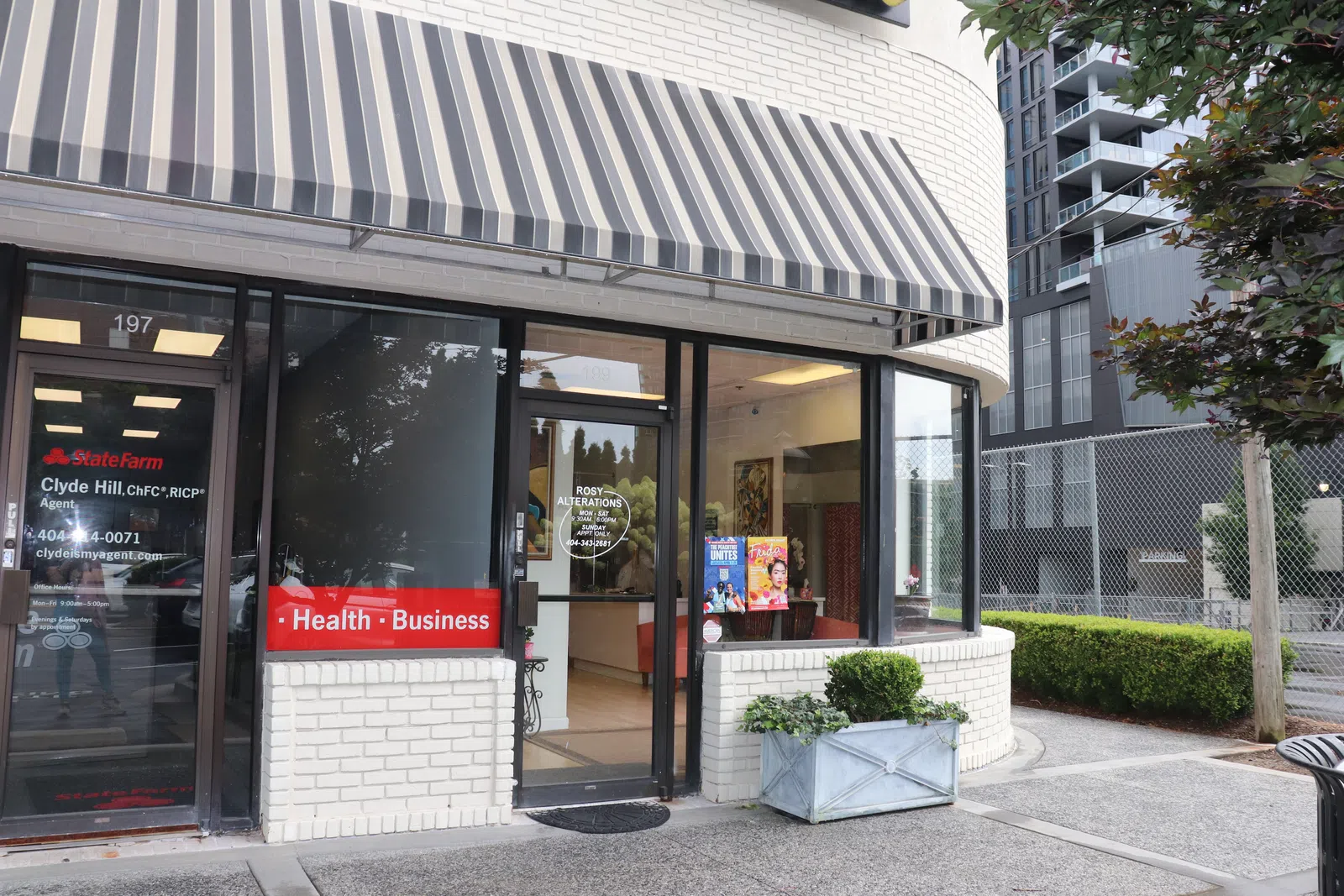 State Farm office entrance with striped awning, health and business sign, next to Rosy Alterations shop window.