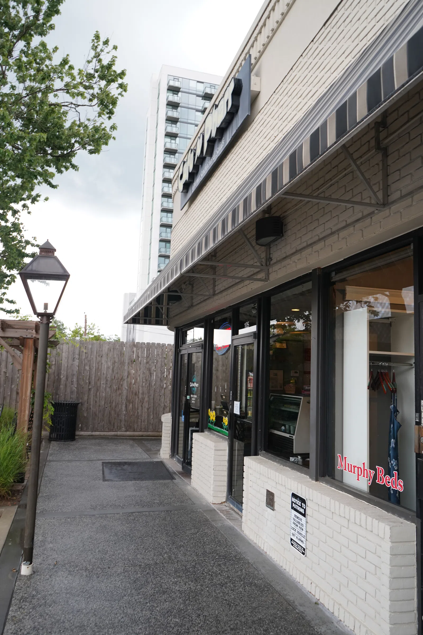 Outdoor view of a beige brick commercial building with striped awning and Murphy Beds sign on window.