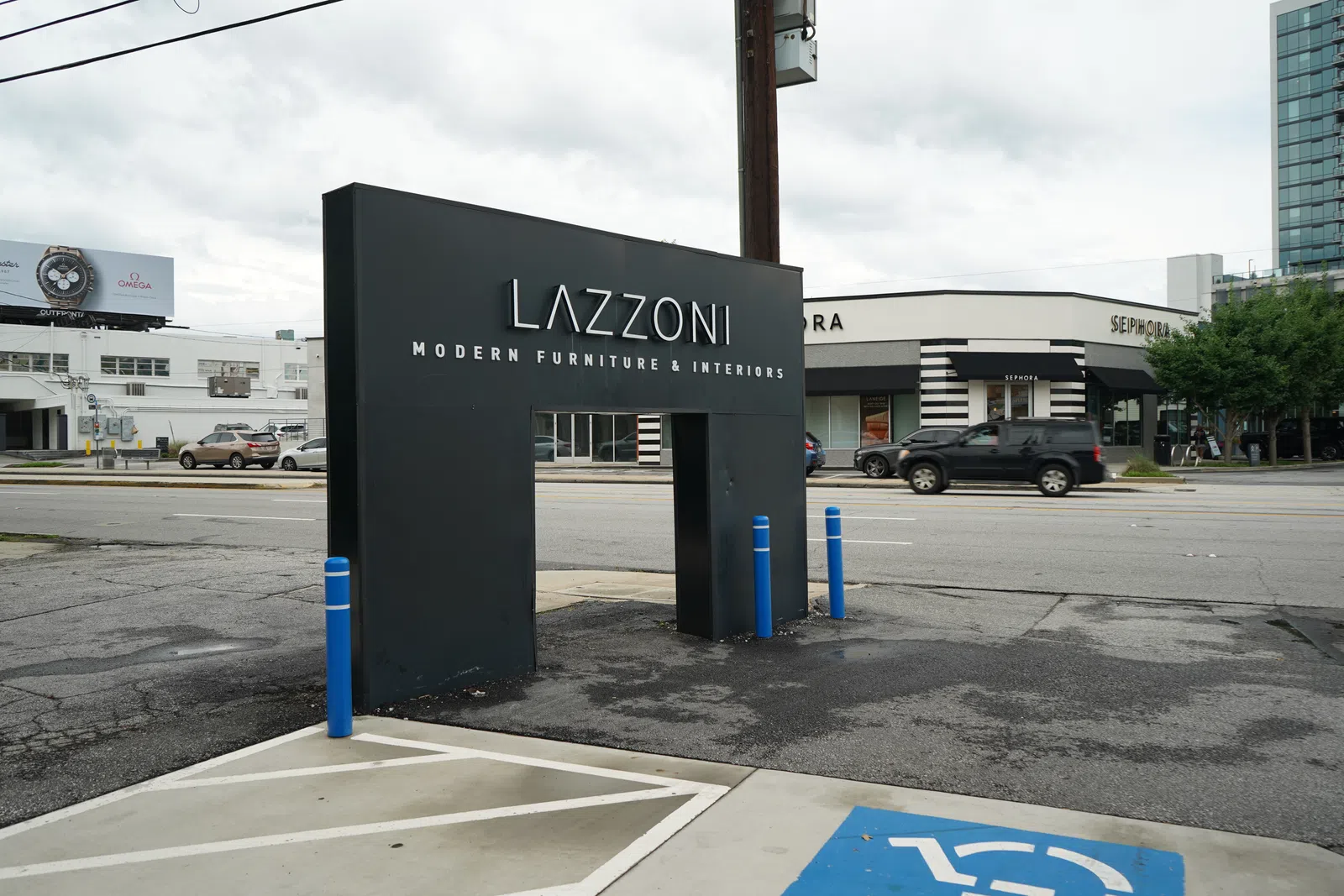 Lazzoni Modern Furniture & Interiors black sign near street with Sephora store and cars in background on cloudy day