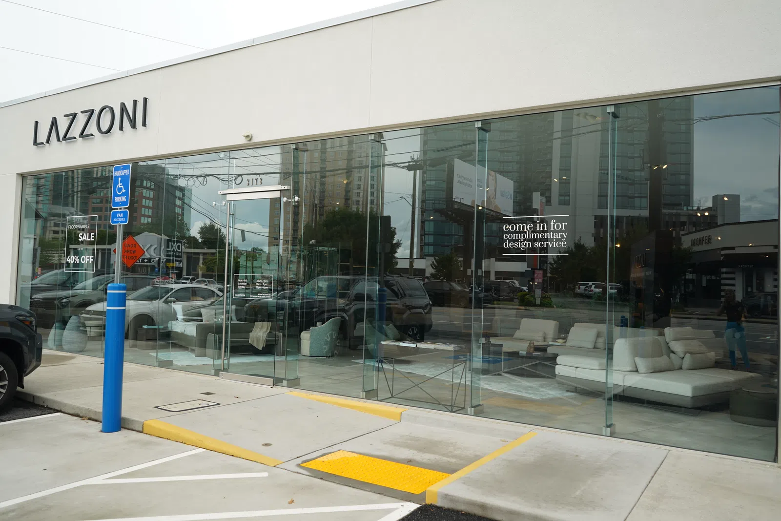 Exterior view of LAZZONI furniture store with glass facade, showcasing modern sofas and a 40% off sale sign.