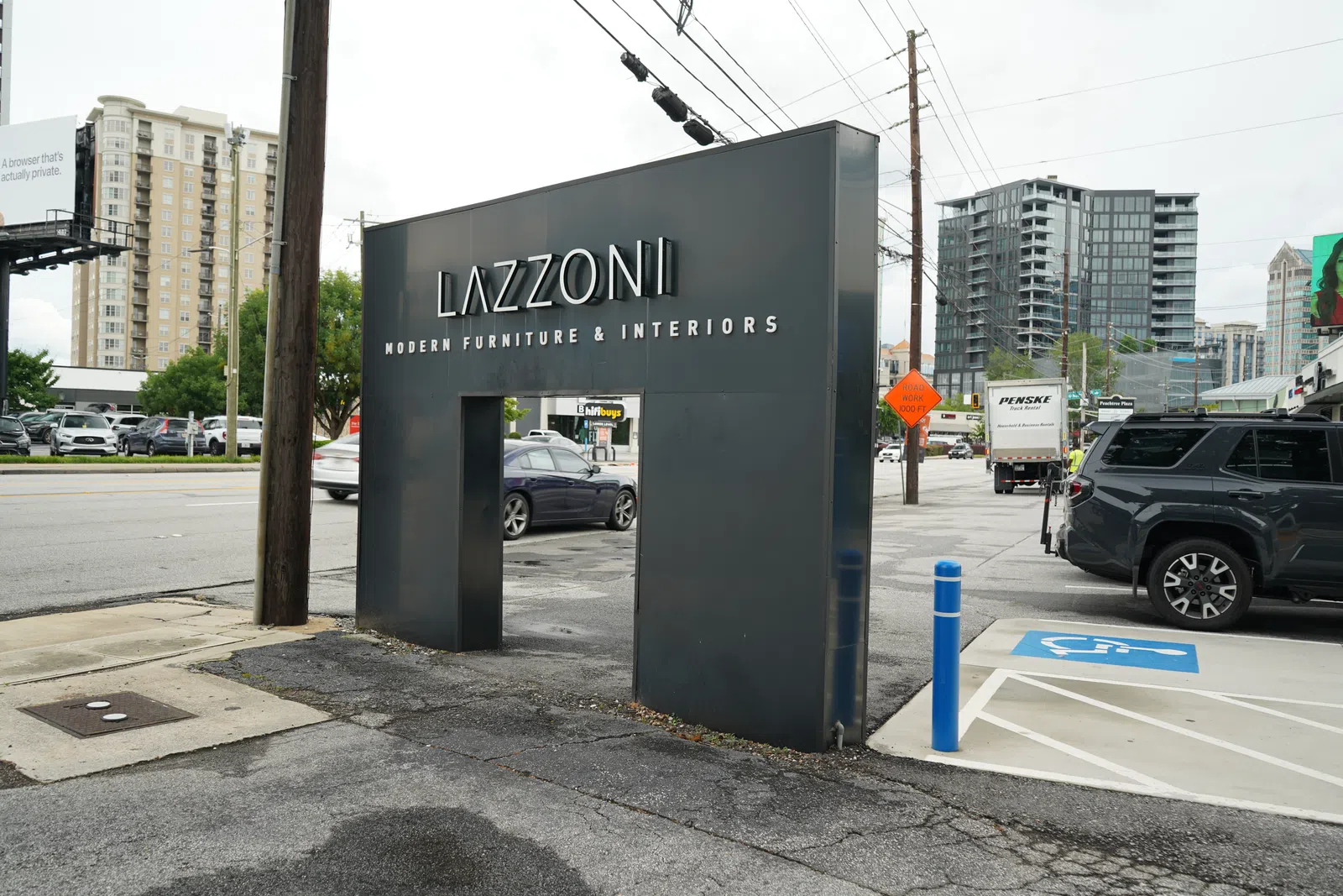 Lazzoni modern furniture and interiors black entrance sign on city street with nearby cars and buildings
