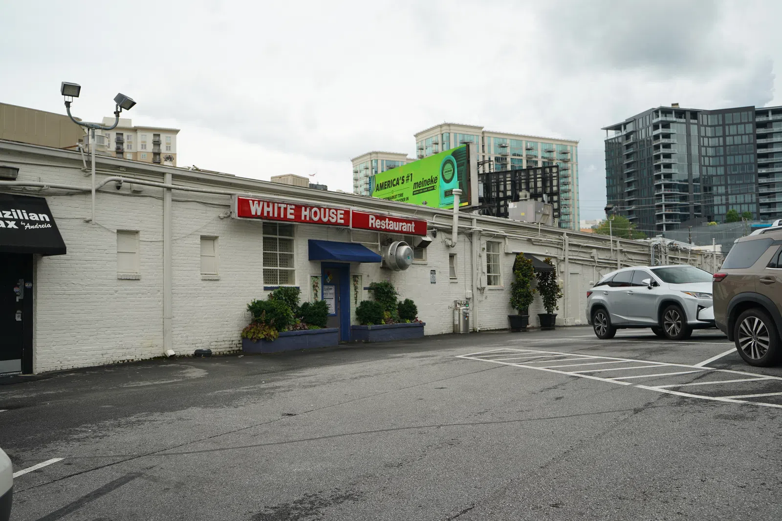Exterior of White House Restaurant with parking lot and modern city buildings on a cloudy day
