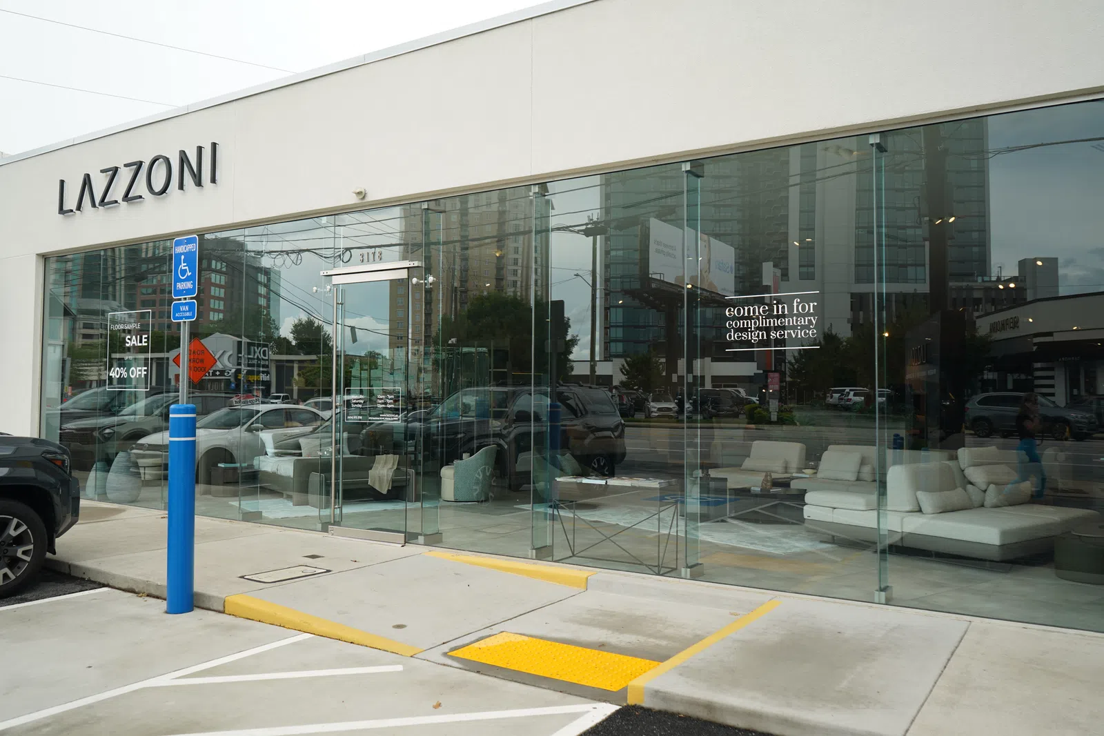 Modern Lazzoni furniture store with glass facade showcasing white sofas and complimentary design service offer.