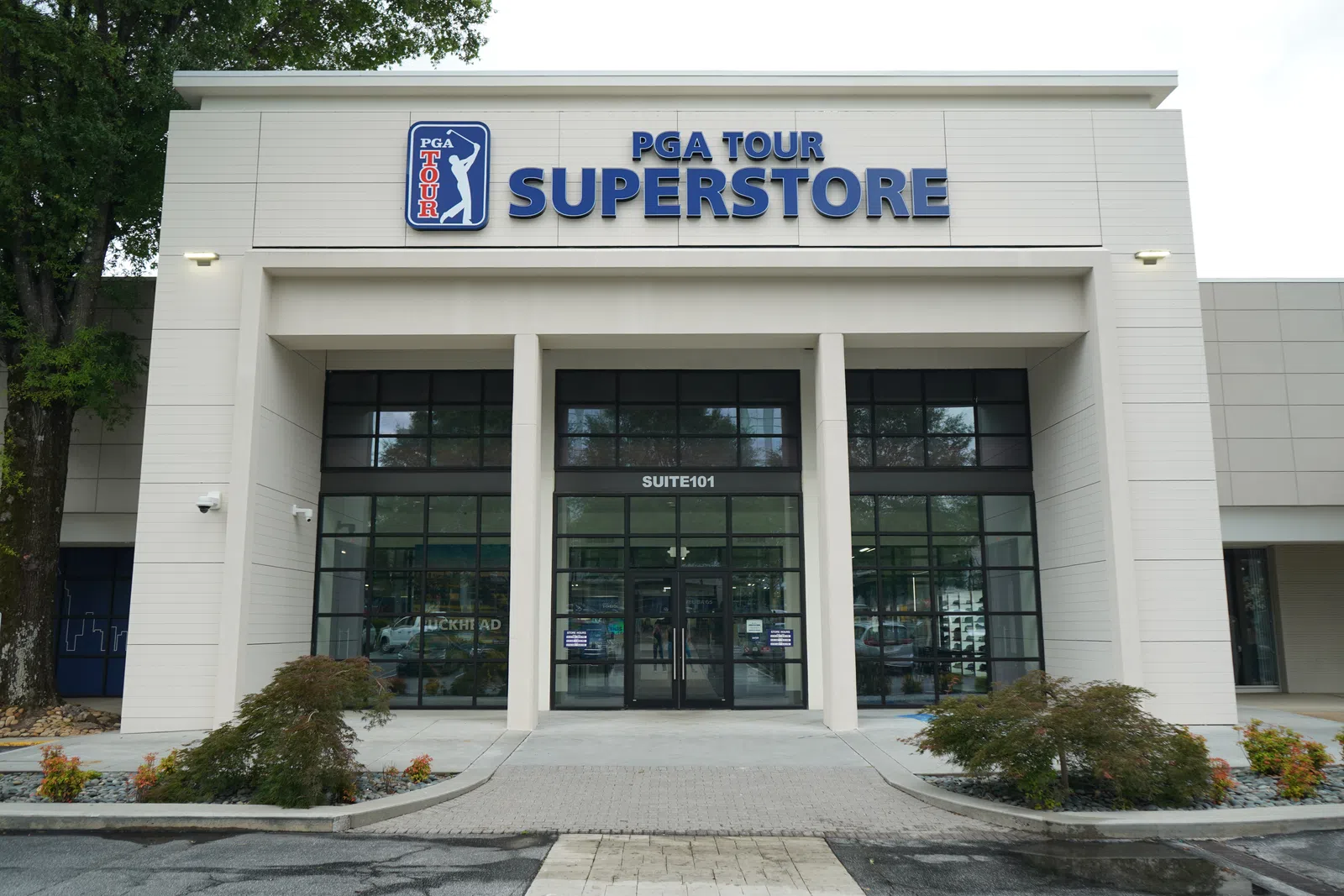 Front entrance of the PGA Tour Superstore with large glass windows and outdoor landscaping under cloudy sky