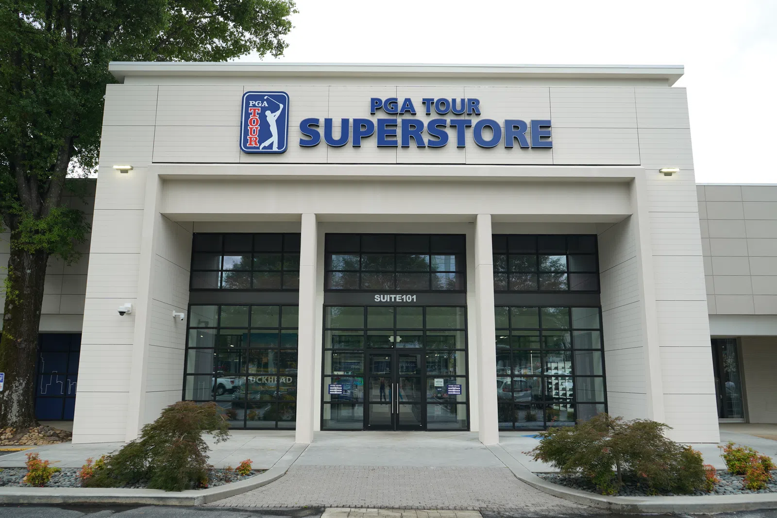 Front entrance of PGA Tour Superstore with glass doors and signage on a cloudy day