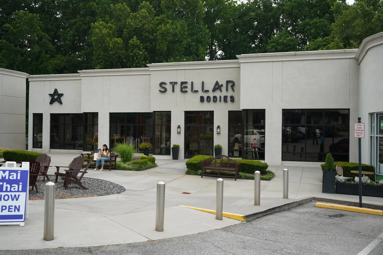 Exterior view of Stellar Bodies fitness studio with outdoor benches, greenery, and parking area in front.