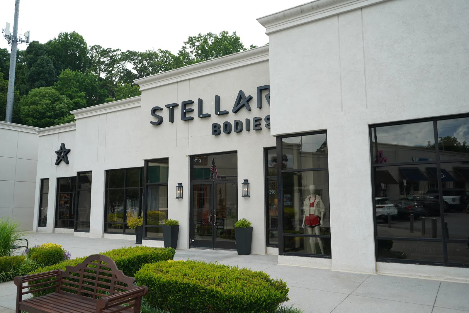 Exterior view of Stellar Bodies fitness center with large windows and green landscaping in front under cloudy sky