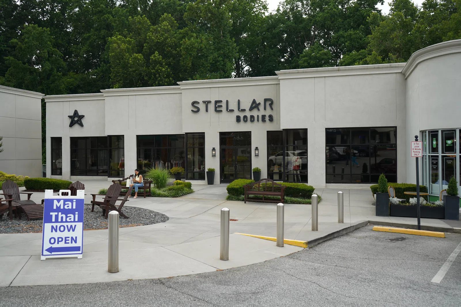 Modern building exterior of Stellar Bodies wellness center with outdoor seating and Mai Thai restaurant sign.