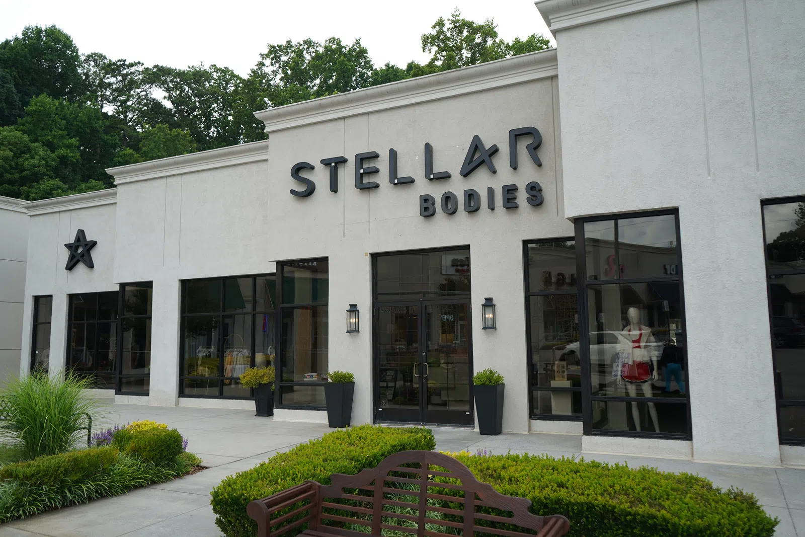 Exterior view of Stellar Bodies fitness studio with modern signage and large windows surrounded by greenery
