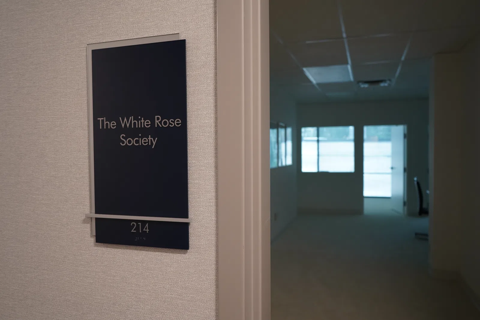 Office door sign for The White Rose Society, room 214, with a dimly lit hallway and office visible inside.