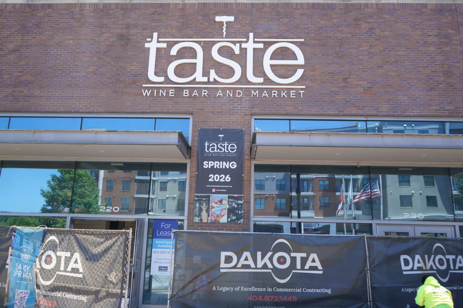 Taste Wine Bar and Market exterior with construction banners for Dakota at a building site in daylight.