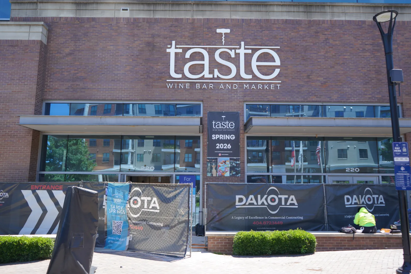Taste Wine Bar and Market storefront with construction banners and a worker in front during daytime