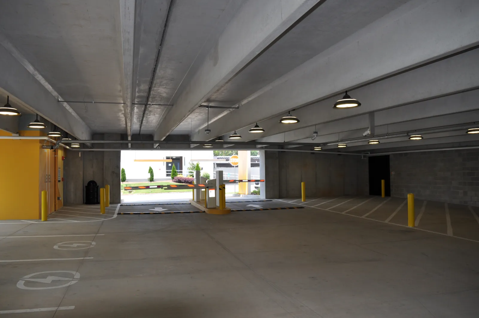 Interior view of an empty underground parking garage with concrete structure and yellow barriers.