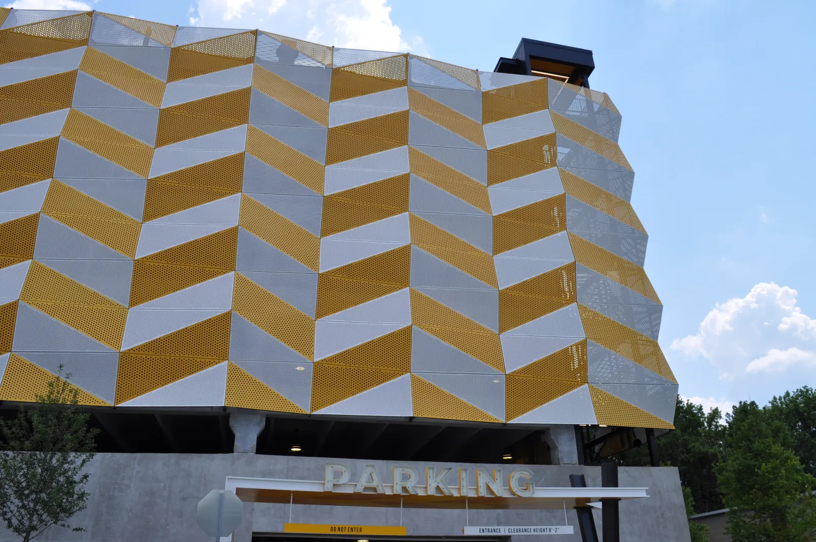 Multi-story parking garage with yellow and white chevron patterned metal facade under a blue sky.