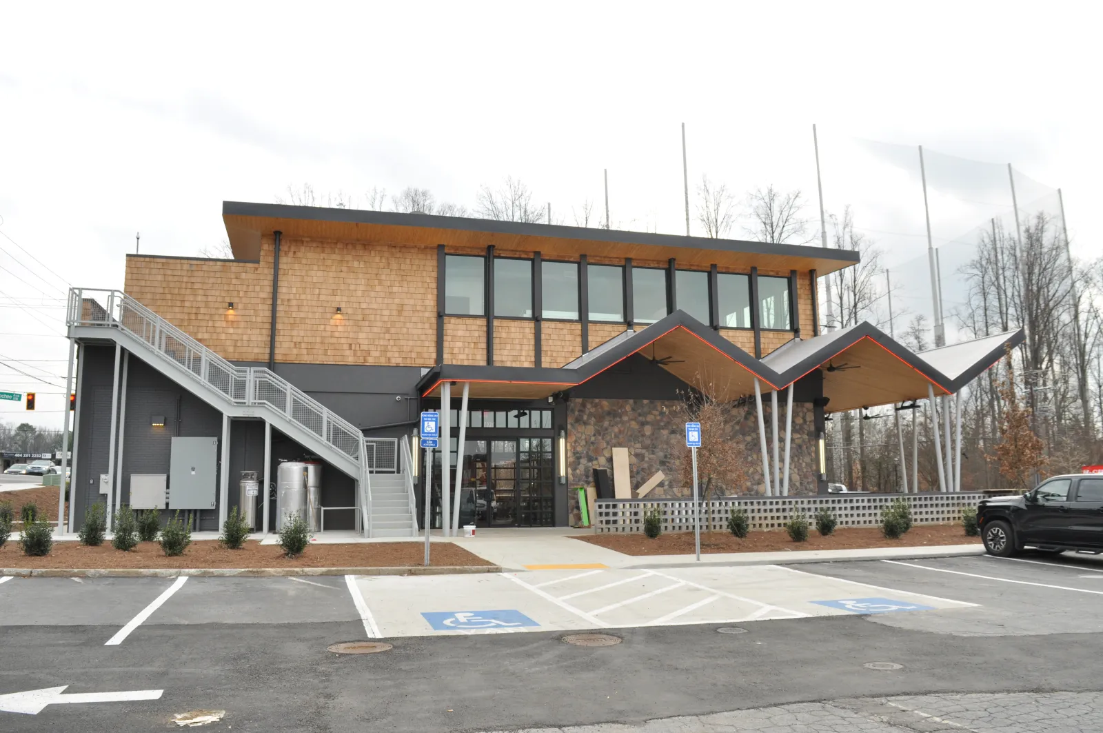 Modern two-story building with angular roof, large windows, parking lot, and disabled parking spots in front.