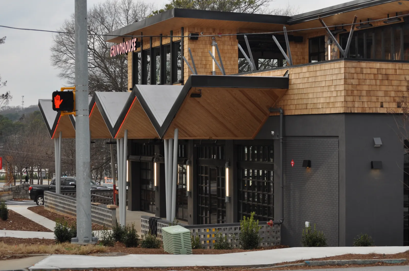 Modern Grindhouse restaurant exterior with wooden accents and geometric roof design on cloudy day