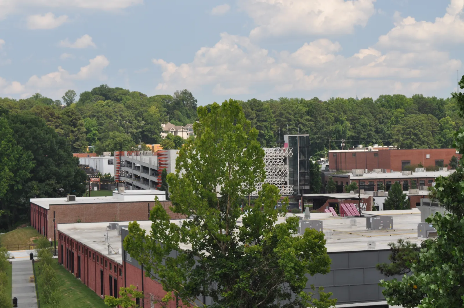 View of red brick buildings with green trees and blue sky with clouds in an urban area