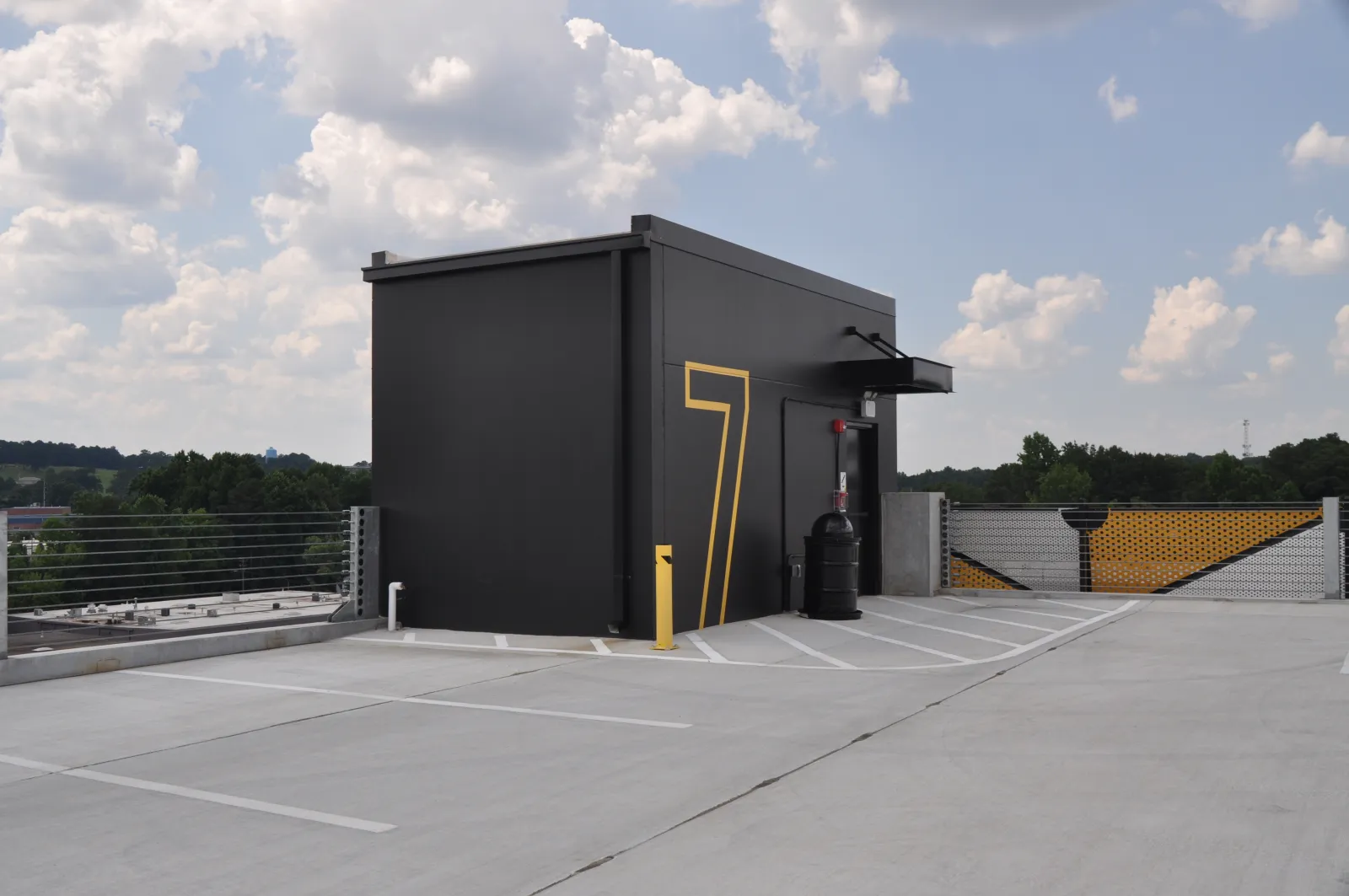 Black rooftop structure with large yellow number 7 painted on side under a partly cloudy sky.