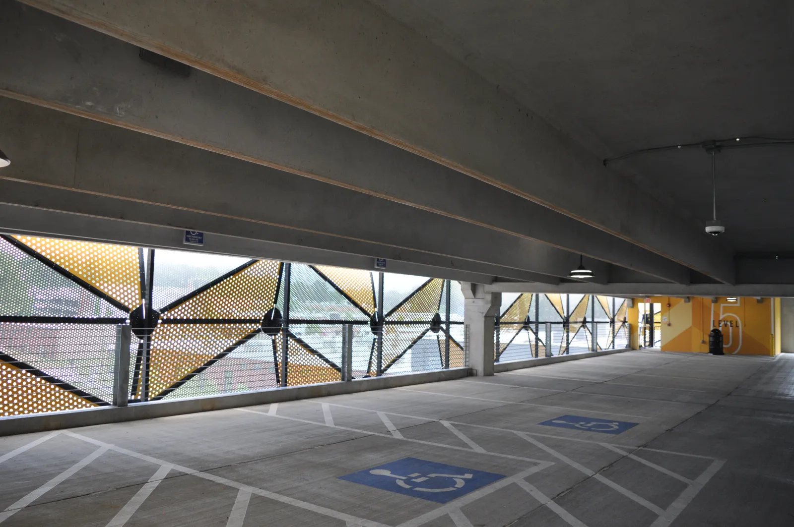 Empty indoor parking garage with handicapped spaces and perforated metal panels allowing natural light.