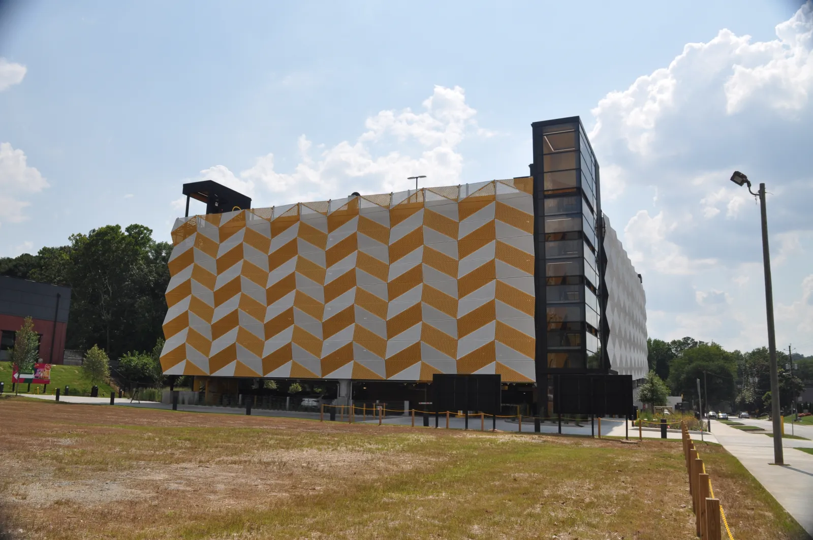 Modern building with a geometric yellow and white patterned facade under a partly cloudy sky.