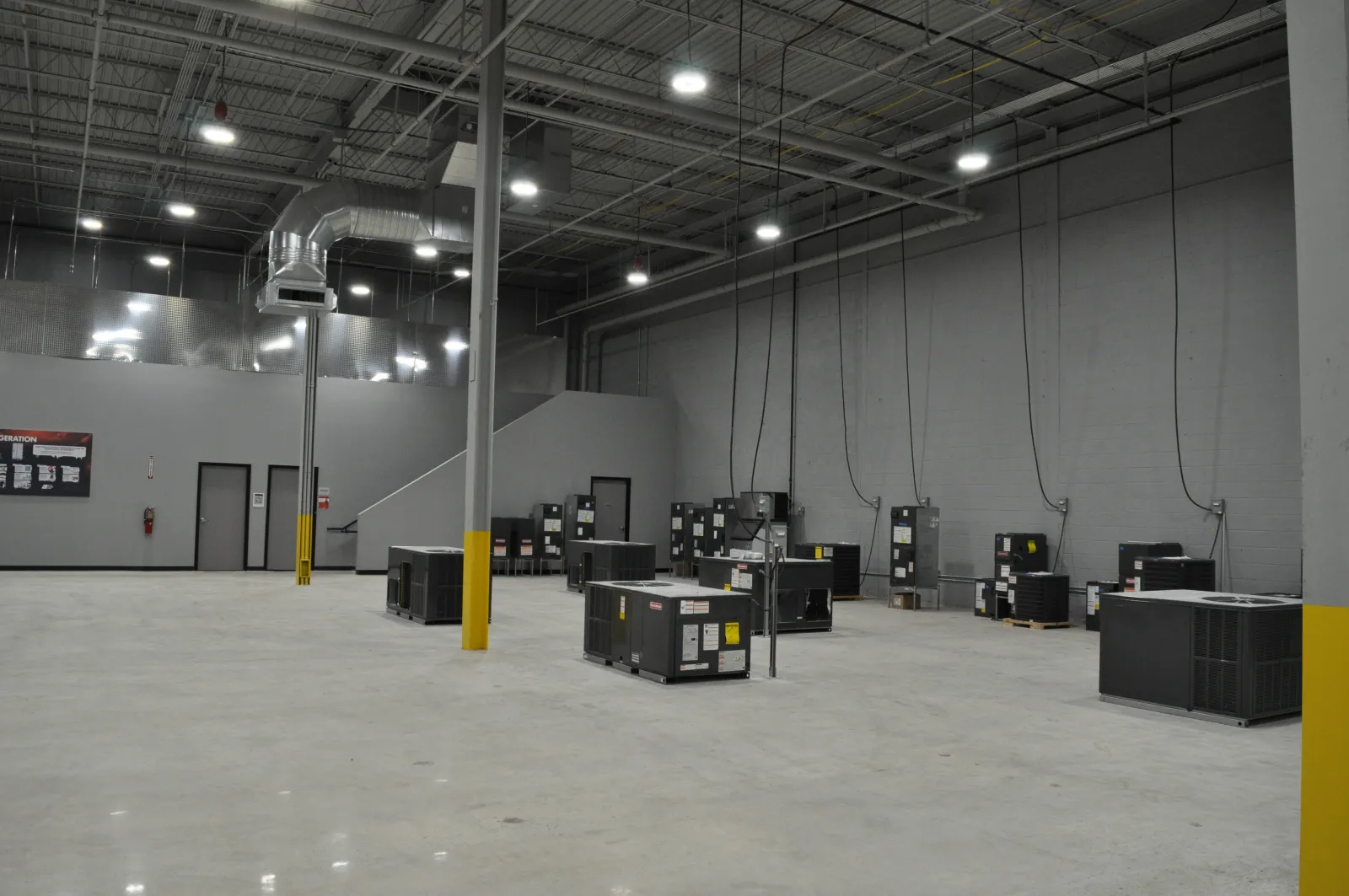 Large industrial warehouse with HVAC units on a polished concrete floor under high ceiling lights
