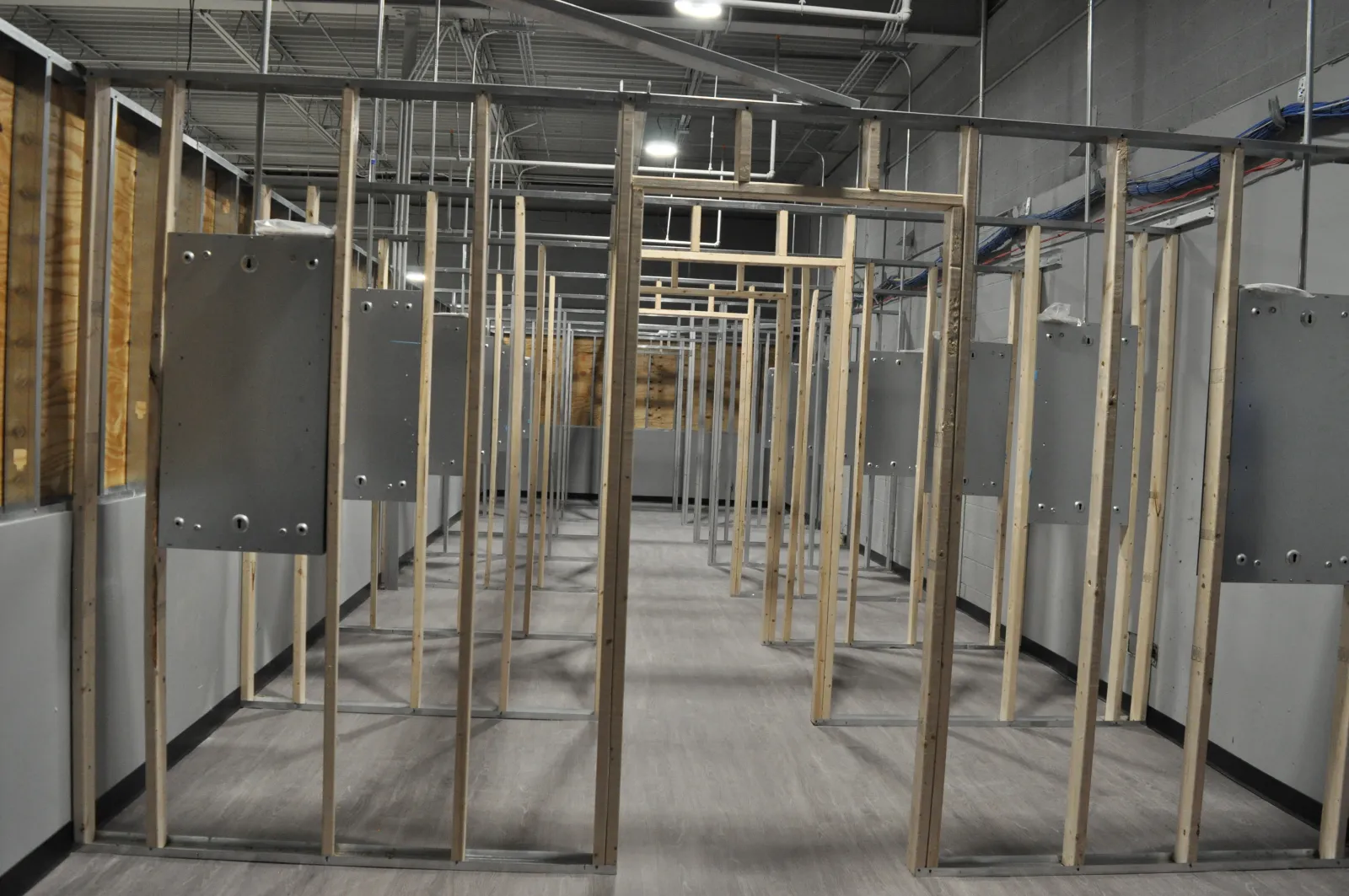 Indoor shooting range with metal targets mounted on wooden frames in a spacious industrial building.