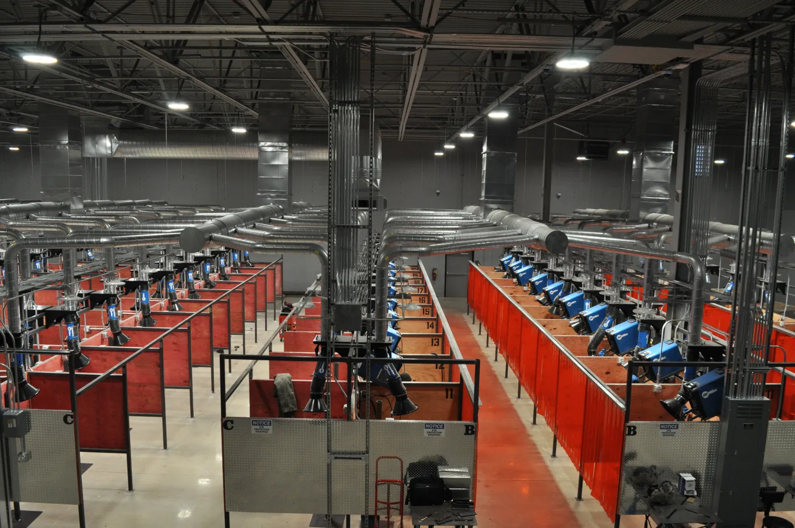 Interior view of a spacious industrial welding workshop with multiple welding stations and ventilation systems.
