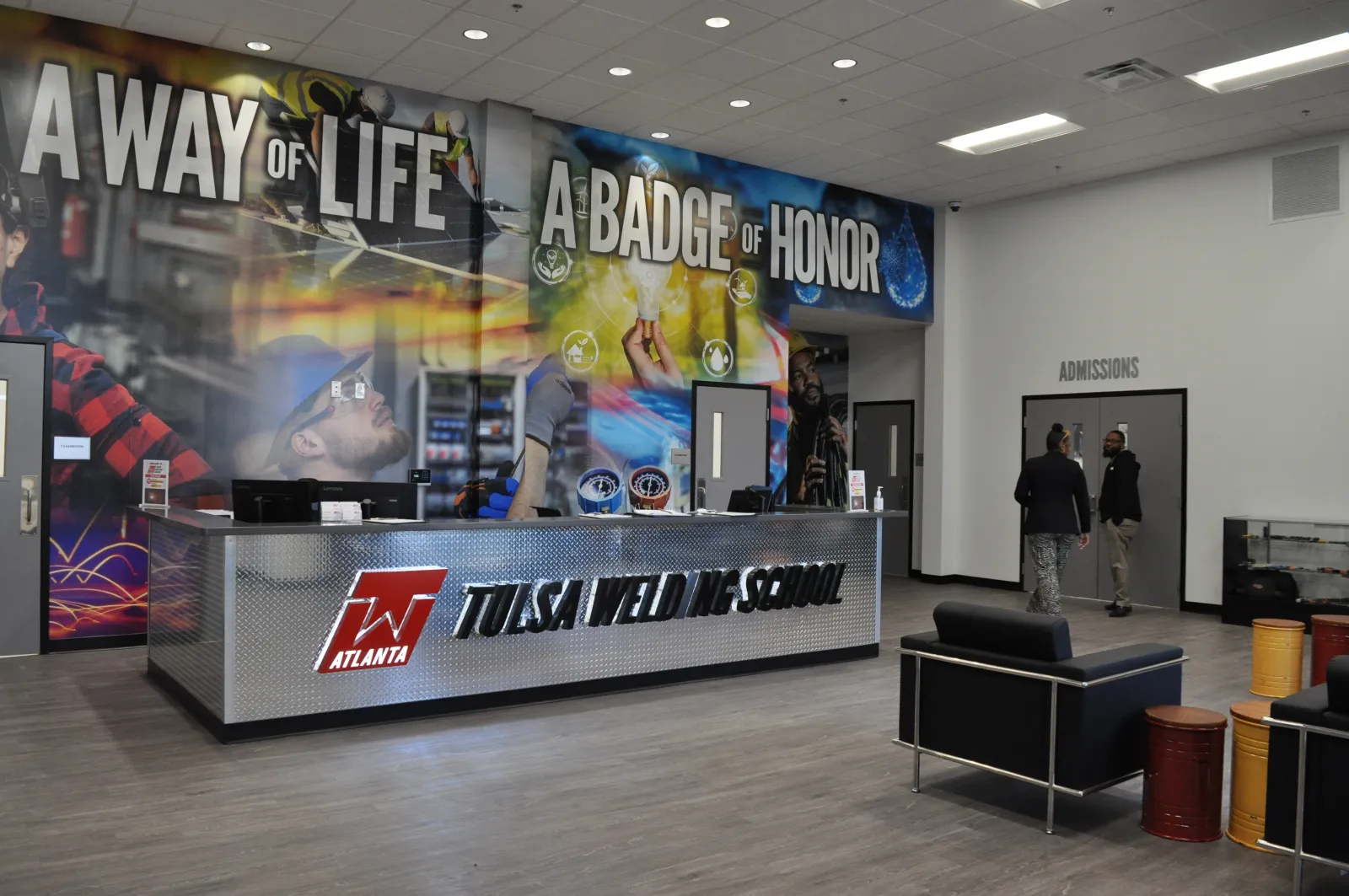 Interior of Tulsa Weld Tech School with a reception desk and wall mural displaying motivational phrases.