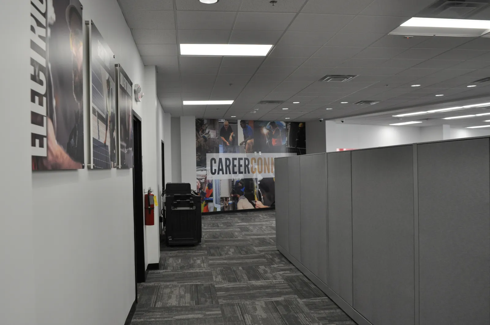 Office hallway with gray cubicles and career conference banner at the end of the corridor.