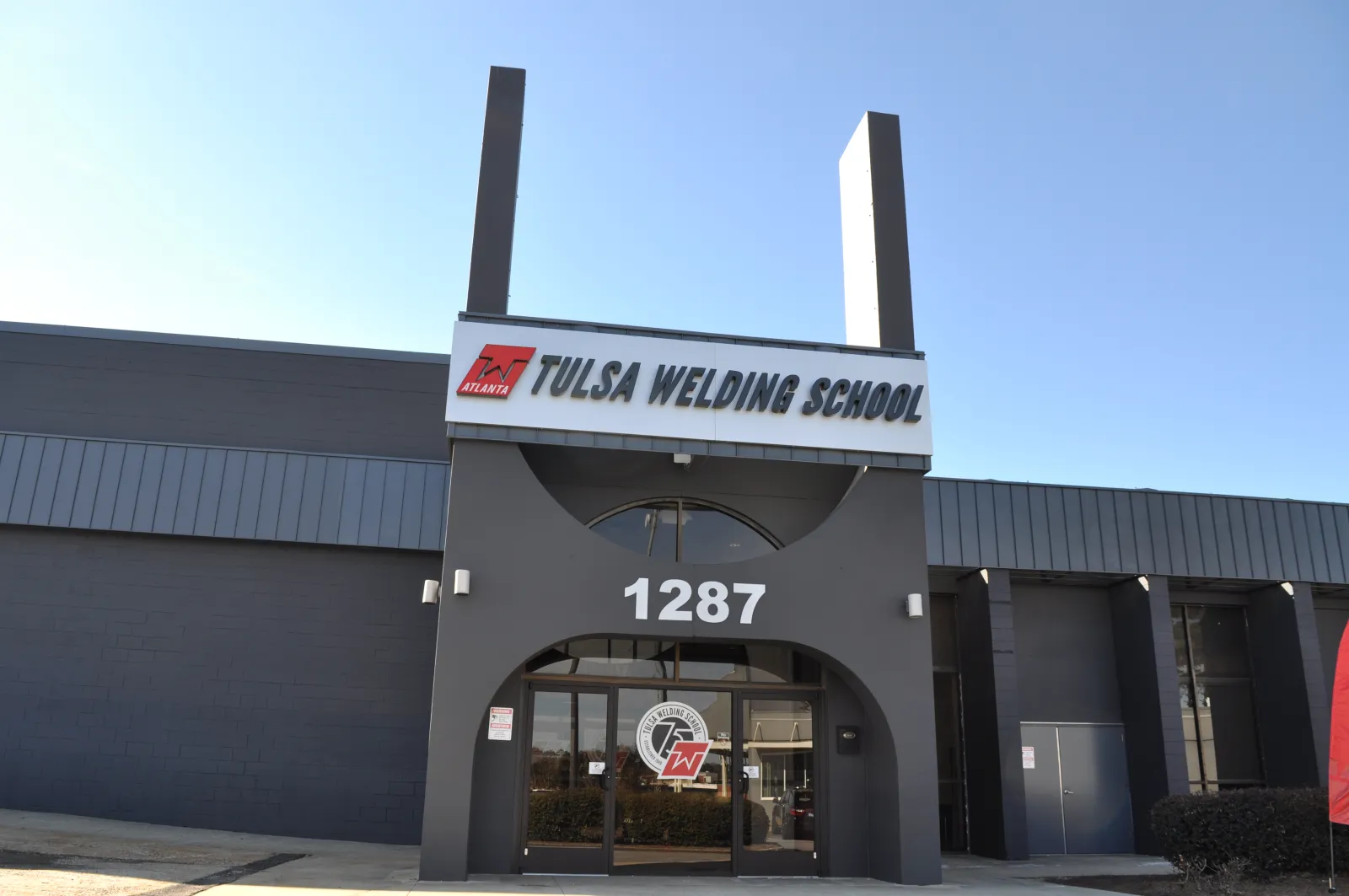 Front entrance of Tulsa Welding School building with clear signage and address number 1287 on a sunny day