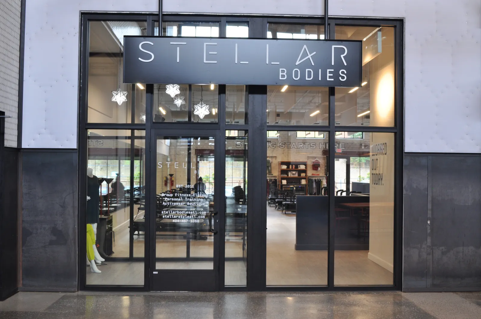 Modern black and glass storefront of Stellar Bodies fitness and activewear boutique with visible interior and lighting.