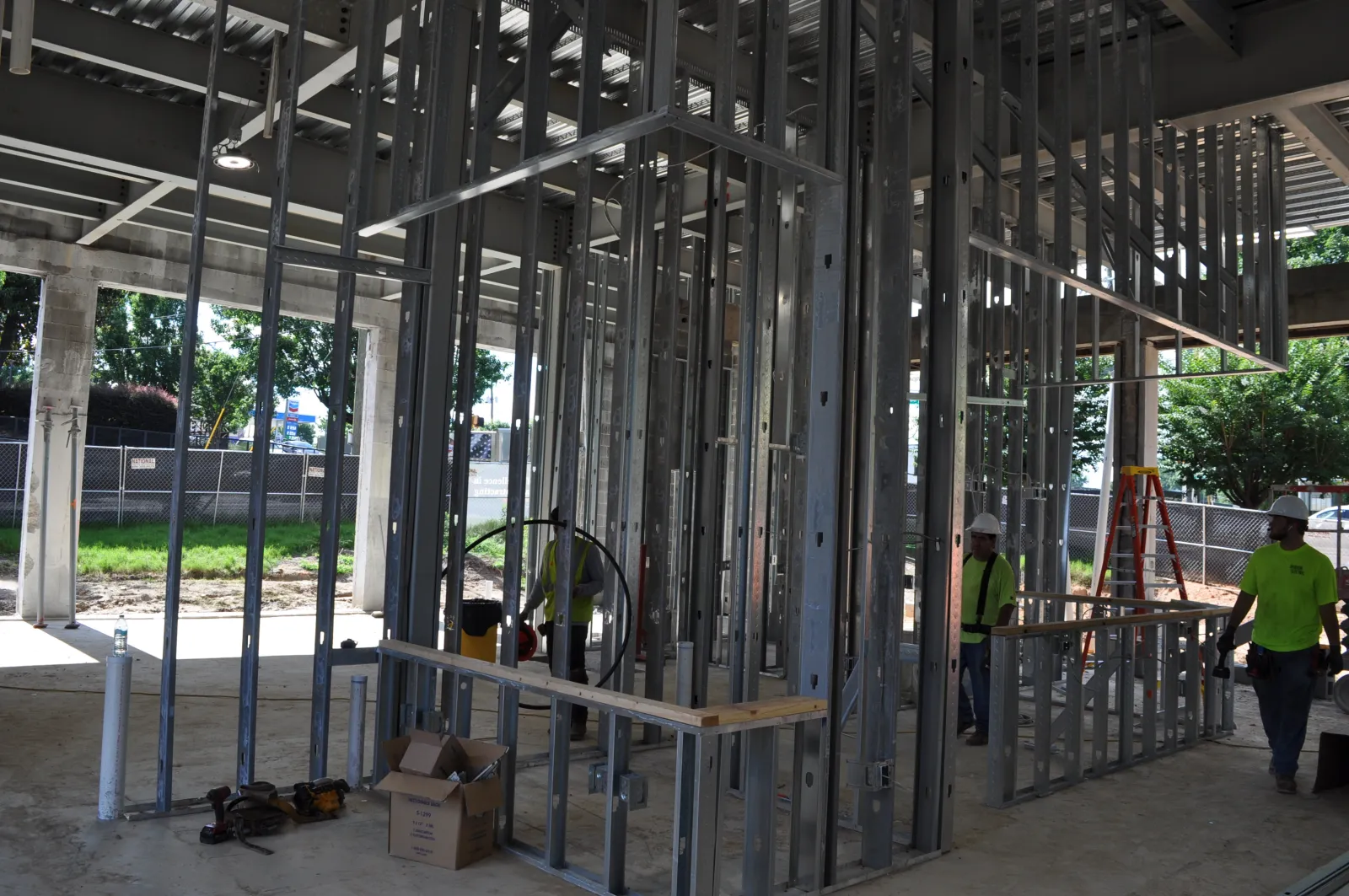 Construction workers installing metal framing inside a building under construction with tools and materials around.