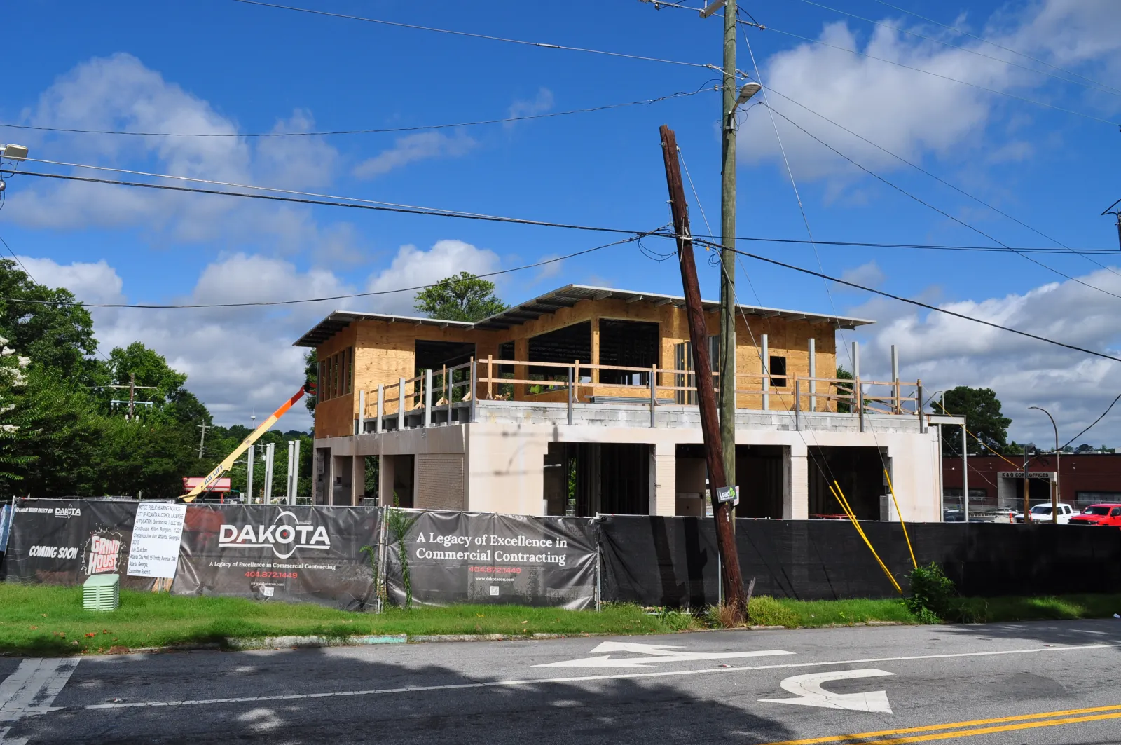 Two-story commercial building under construction with wooden framing and Dakota contracting signage on fencing.